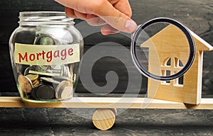Miniature house and glass jar with coins on the scales. The inscription `mortgage`. credit for property / apartment. Business loan