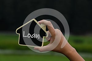 Miniature house in hands with text loan on it.