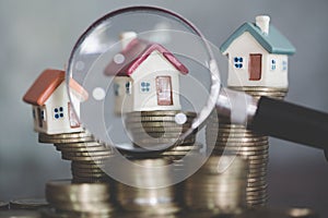 Miniature of house with magnifying glass and coin, choice of location for the construction, of mortgage, rental housing, House