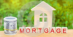 Miniature house and money. Wooden blocks and the inscription `mortgage`. credit for property / apartment. Business loans for real