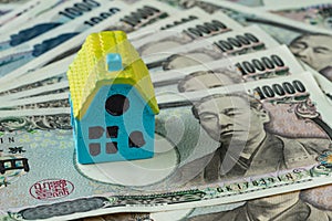 Miniature house on pile of japanese yen banknotes as real estate