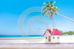 Miniature house with red roof on tropical sand beach over blurred cloudy sky on day noon light.Image for property real estate inve