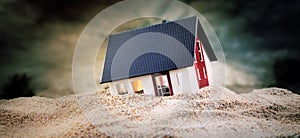 Miniature of house standing in sand