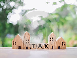 Miniature house and wooden blocks with the word TAX. The concept of paying tax for house and property