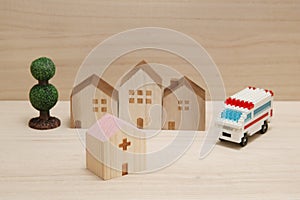 Miniature houses, hospital and ambulance on wood.