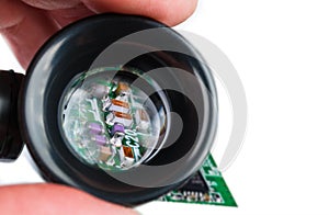 Miniature inductors  resistors and capacitors in loupe on a white background