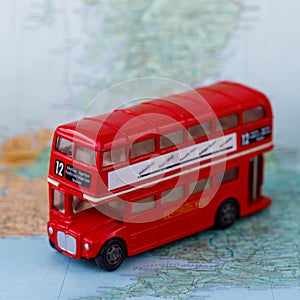 Miniature kid toy red Loondon bus on the map of united kingdom. Side view. Square instagram format