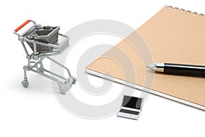 Miniature laptop with small shopping cart on white background.