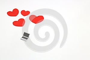 Miniature laptop and some red hearts on white background.