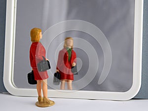 Miniature little woman in red coat looking herself in the mirror