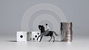Miniature man riding a horse. Dice and coin stacks. Concepts about the probability of winning a race. photo