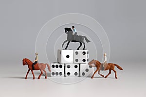 Miniature man riding a horse and white dice. Concepts about the probability of winning a race.