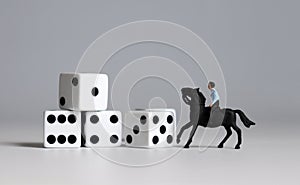 Miniature man riding a horse and white dice. Concepts about the probability of winning a race. photo