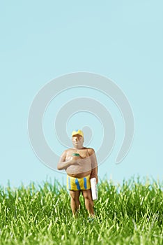 Miniature man in swimsuit standing on the grass