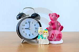 Miniature married couple and teddy bear and clock on wooden. concept for wedding & valentine Day