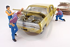 Miniature mechanics work on a gold toy car.