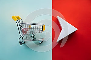 Miniature metallic shopping cart with a yellow handle, next to a red and white triangular object photo