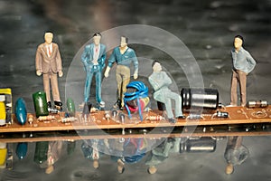 Miniature model of businessmen at the cpu on a reflective surface.