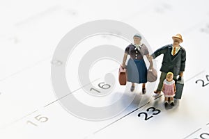 Miniature model family people, travelers standing on the calendar, traveling and planning concept