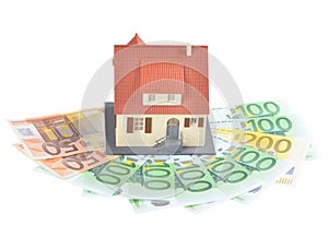 Miniature model of houses on stacked euro banknotes, on isolated white background. Real estate investment concept. Saving money fo