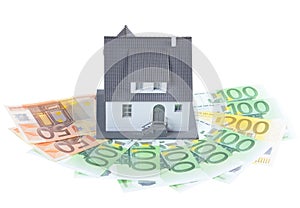 Miniature model of houses on stacked euro banknotes, on isolated white background. Real estate investment concept. Saving money fo