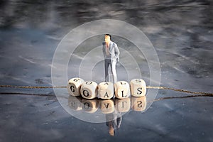 Miniature model of man and wooden cubes with goals inscription strung on a thread