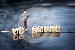 Miniature model of man and wooden cubes with my goals inscription strung on a thread