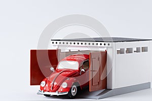 Miniature model red car in garage on white background.