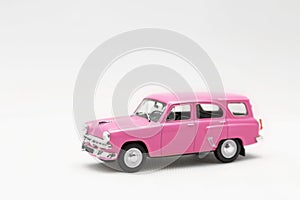 Miniature model of a toy pink retro car on a white background.