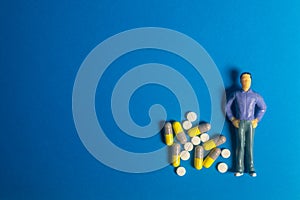 Miniature models and Pills, drugs on blue background. Healthcare concept