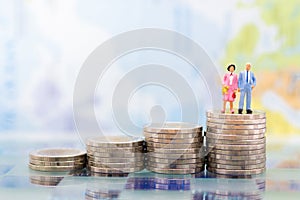 Miniature people, adult couple figure standing on top of stack coins . Image use for background retirement planning, Life insuranc