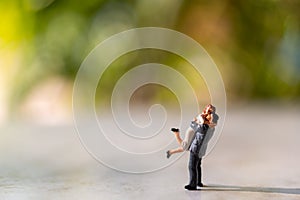 Miniature people : Bride and groom outdoors with green bokeh background and  copy space for text