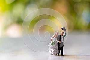 Miniature people : Bride and groom outdoors with green bokeh background and  copy space for text