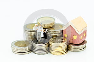 Miniature people : Bride and groom standing on stack of coins with wedding suite. Image use for saving money , accumulate money photo