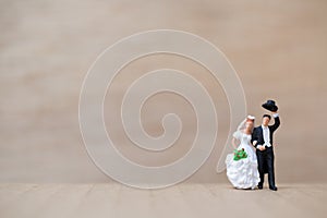 Miniature people : Bride and groom on wooden background with copy space for text