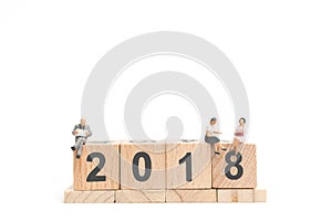 Miniature people business concept sitting on wooden block number