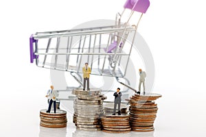 Miniature people: Business standing on stack of coins with shopping cart. shopping and business concept.
