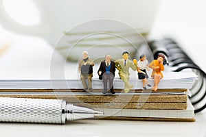 Miniature people : Business team sitting on book and having a coffee break. Image use for business concept