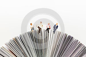 Miniature people, Business team sitting on book, reading news paper,using as background business, education concept photo