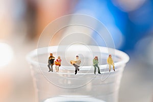 Miniature people, business team sitting on cup of coffee