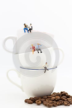 Miniature people : Business team sitting on cup of coffee and ha