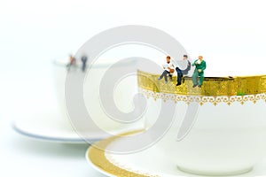 Miniature people : Business team sitting on cup of coffee and having a coffee break. Image use for business concept