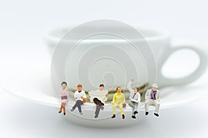 Miniature people : Business team sitting on cup of coffee and having a coffee break. Image use for business concept