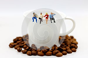 Miniature people: business team sitting on cup of coffee with morning news. Coffee time of business concept