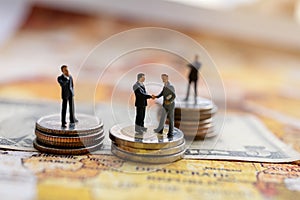 Miniature people: Businessman handshake with coins stack on world map,  Investment, agreement, partnership and business concept