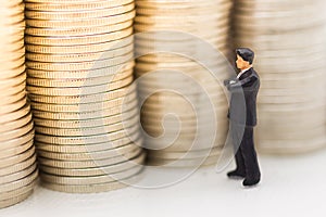 Miniature people, Businessman looking for stack of coins using as background money growth up, saving, financial, business concept