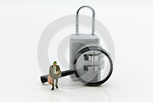 Miniature people: Businessman with a magnifying glass and master key encoding. Image use for background security system