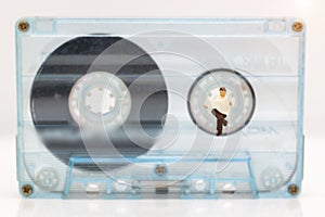 Miniature people: Businessman reading newspaper on tape Cassette