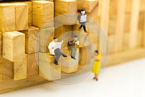 Miniature people: businessman reading newspaper on wooden block. Image use for background education or business concept