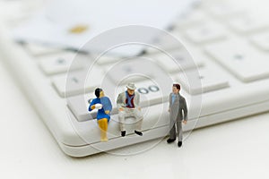 Miniature people: Businessman sitting on calculator for calculating money, tax, monthly/yearly. Image use for finance, business